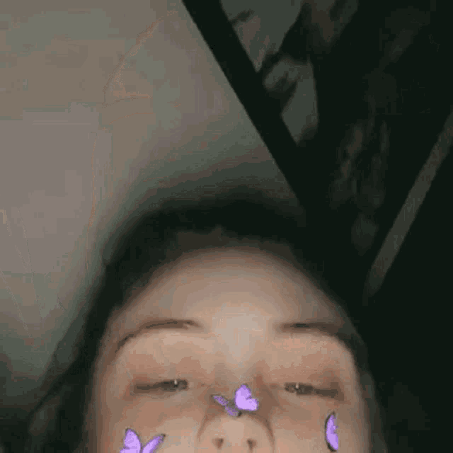a close up of a woman 's face with purple butterflies on her face .