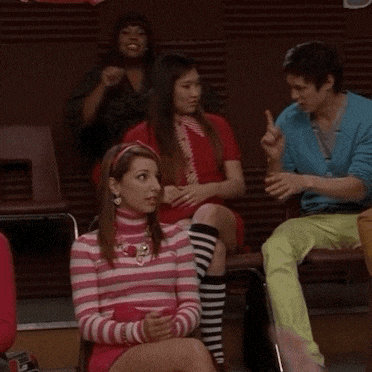 a girl in a pink and white striped sweater sits in a crowd of people