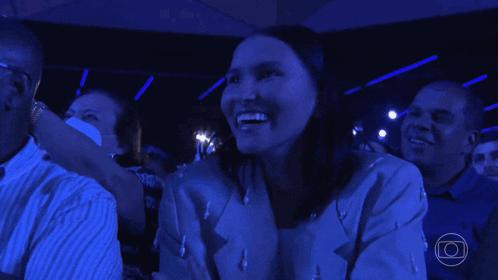 a woman in a blue jacket is laughing in a crowd