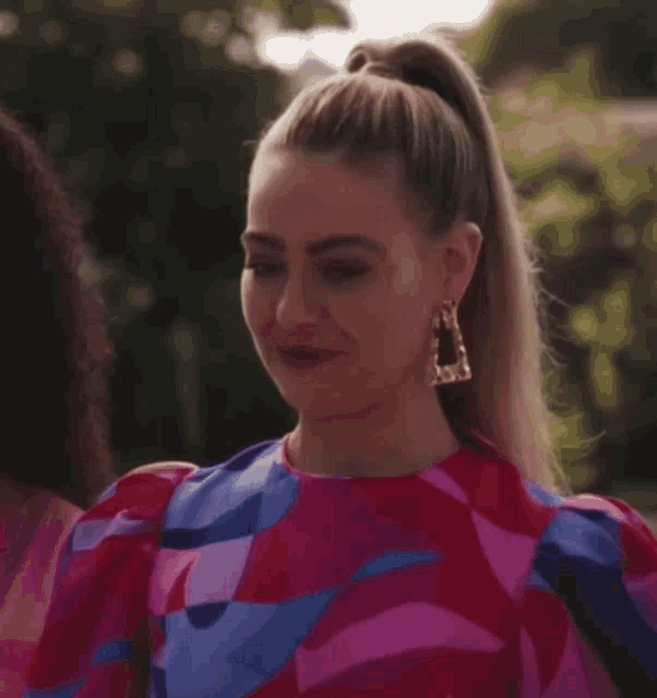 a woman in a colorful dress is smiling while standing next to another woman .