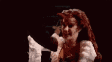 a woman in a white dress is holding a red rose .