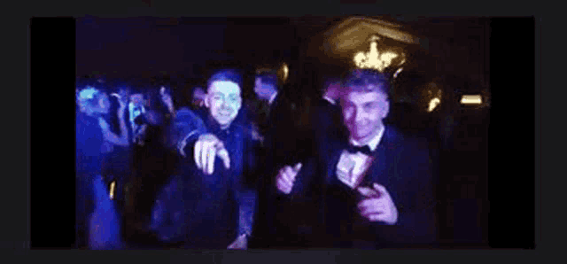 two men are dancing in a dark room with blue lights