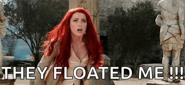 a woman with red hair is standing in front of a statue and says they floated me !!!