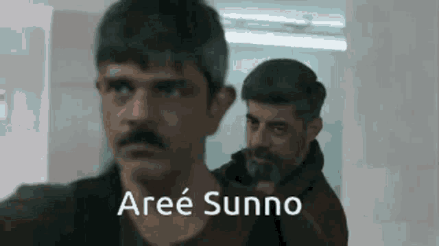 two men are standing next to each other in a hallway and one of them is holding a gun and says aree sunno .