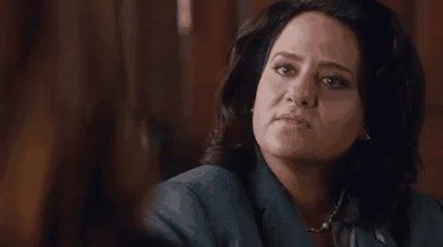 a woman in a suit and necklace is sitting at a table .