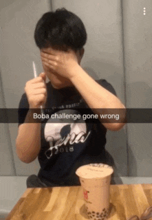 a man in a boba challenge shirt is covering his face with his hands