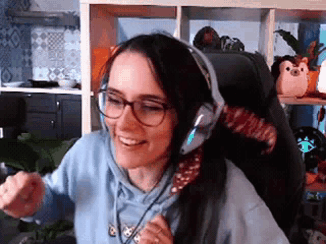 a woman wearing headphones and glasses is sitting in a chair in a room .