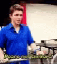 a man in a blue shirt is holding a barbell in a classroom .