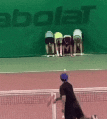 a group of people are standing on a tennis court in front of a babolat banner