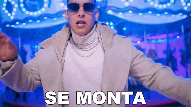 a man wearing sunglasses and a white turtleneck is standing in front of a carousel and says se monta