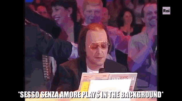 a man sitting in front of a crowd with the words " sesso senza amore plays in the background " written below him