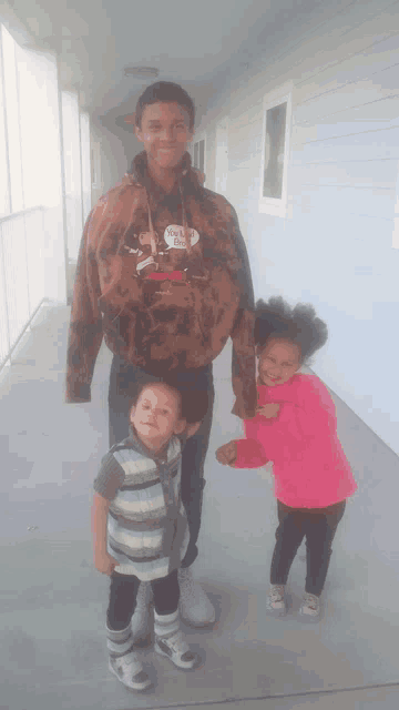 a boy wearing a hoodie that says hello kitty on it poses with two children