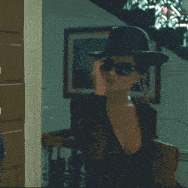a woman wearing a hat and sunglasses is sitting in a chair
