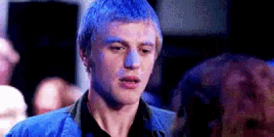 a man with blue hair is talking to another man in a crowd