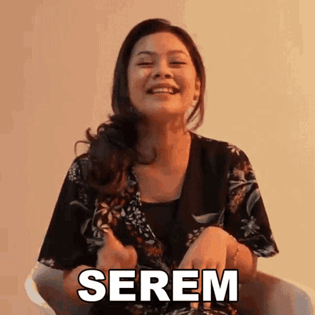 a woman is sitting in a chair and smiling with the word serem written above her