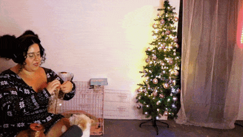 a woman is sitting in front of a small christmas tree