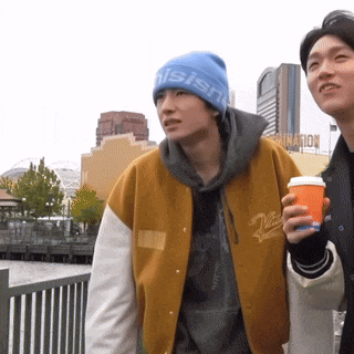 a man wearing a beanie that says " nishi " stands next to another man