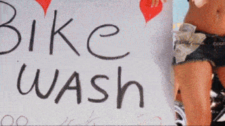 a sign for a bike wash with a woman on a motorcycle behind it