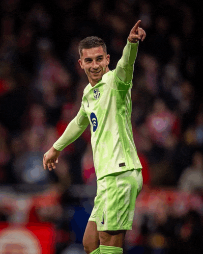 a soccer player wearing a green jersey with the number 6 on it is pointing up