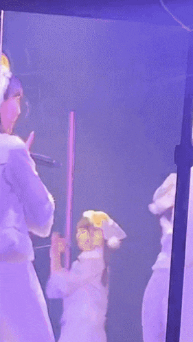 a woman in a white robe singing into a microphone on stage