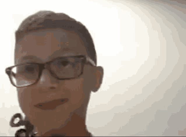 a young boy wearing glasses is looking at the camera and smiling .