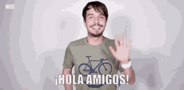 a man wearing a green shirt with a bicycle on it says hola amigos