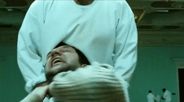 a man in a white shirt is laying on another man 's back
