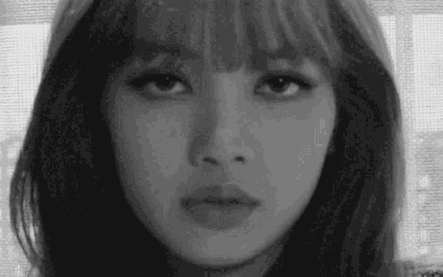 a black and white photo of a woman 's face with bangs .