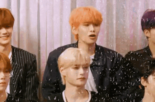 a group of young men standing next to each other in front of a curtain .