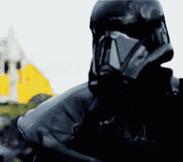 a close up of a storm trooper 's helmet with a yellow building in the background
