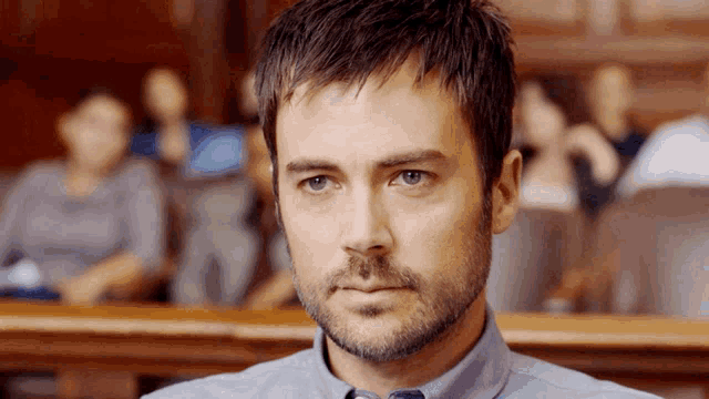 a man with a beard is sitting in a courtroom