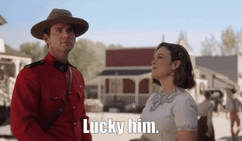 a man in a red uniform is standing next to a woman and says lucky him