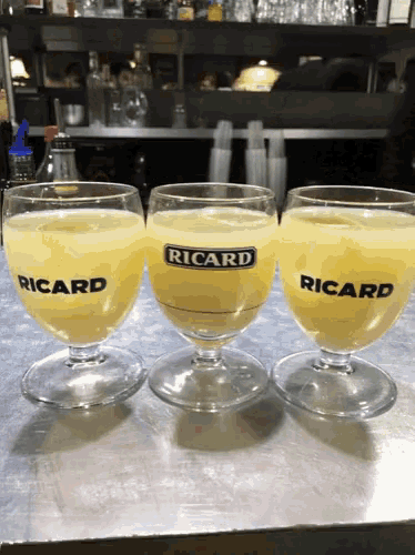three glasses of ricard sit on a counter top