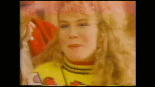 a woman with blonde hair is wearing a yellow sweater and a red hat .