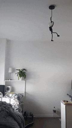 a room with a bed and a lamp that looks like a monkey hanging from the ceiling