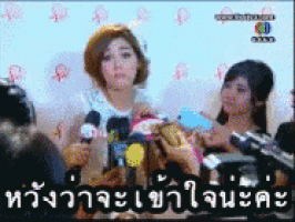 a woman in a hat is being interviewed by a group of people in a room