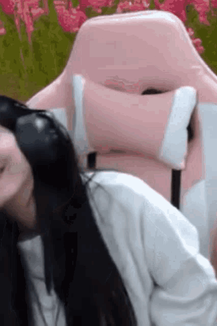 a woman wearing headphones is sitting in a pink chair .