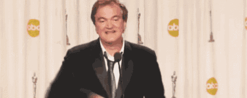 a man in a suit and tie is standing in front of a microphone giving a peace sign .
