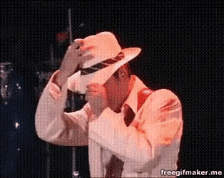 a man in a white suit and hat is dancing on a stage with a freegifmaker.me watermark