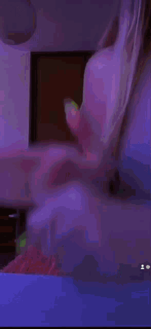 a blurry picture of a woman laying on a bed with a tv in the background