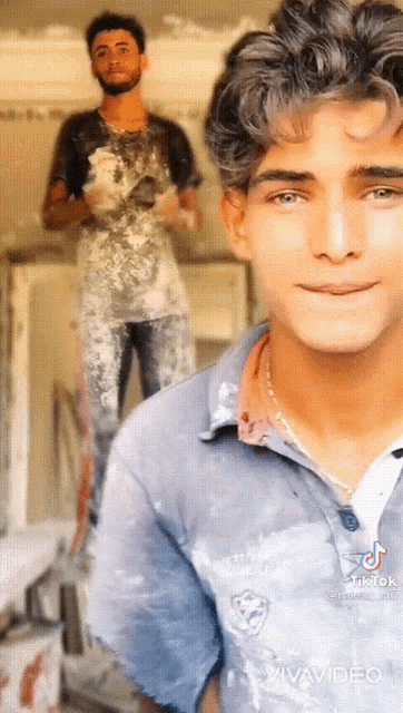 a man in a blue shirt is smiling in front of a man in a black shirt