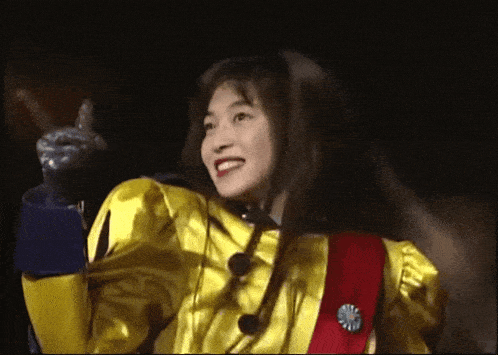 a woman is wearing a yellow jacket and a red sash with a pin that says ' a ' on it