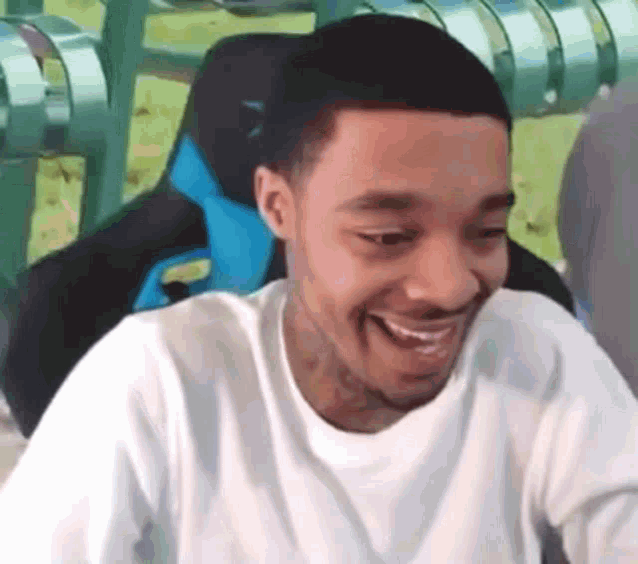 a man is smiling while sitting in a chair with a blue seat .