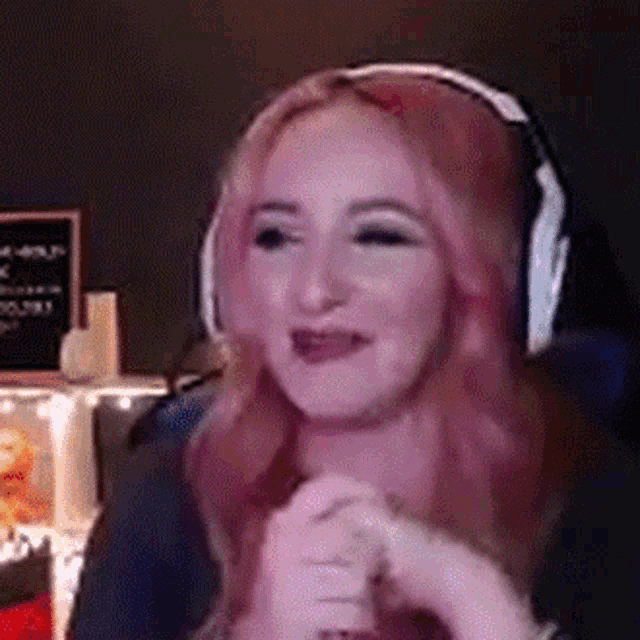 a woman with red hair is wearing headphones and smiling while sitting in a chair .