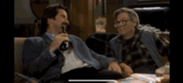 two men are sitting on a couch talking to each other .