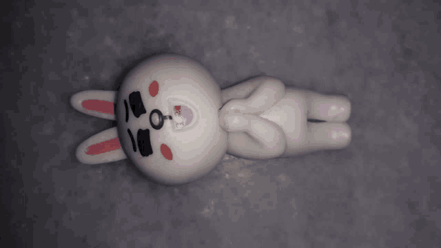 a white bunny with a pink nose and ears is laying down and making a peace sign