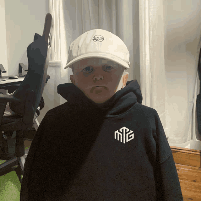 a little boy wearing a white hat and a black hoodie with the letter m on it
