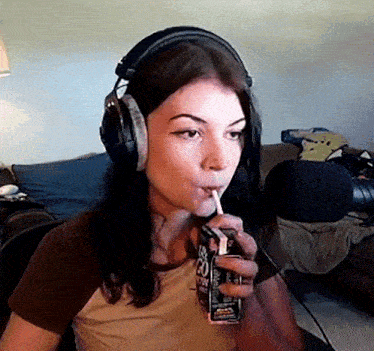 a woman wearing headphones is drinking from a carton of jack daniel 's