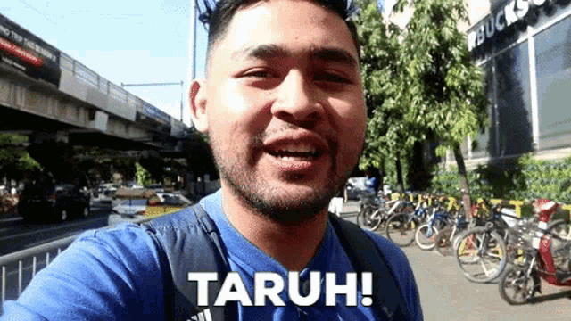 a man in a blue shirt is taking a selfie and says taruh