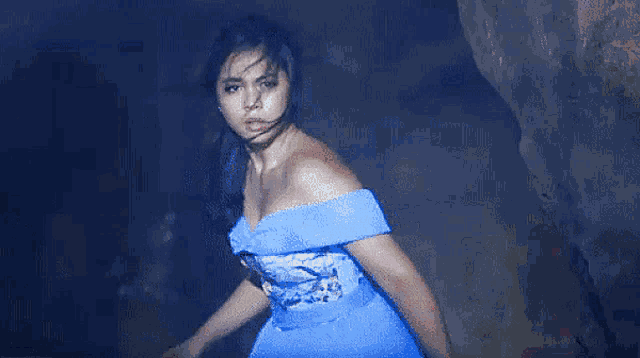 a woman in a blue off the shoulder dress is dancing